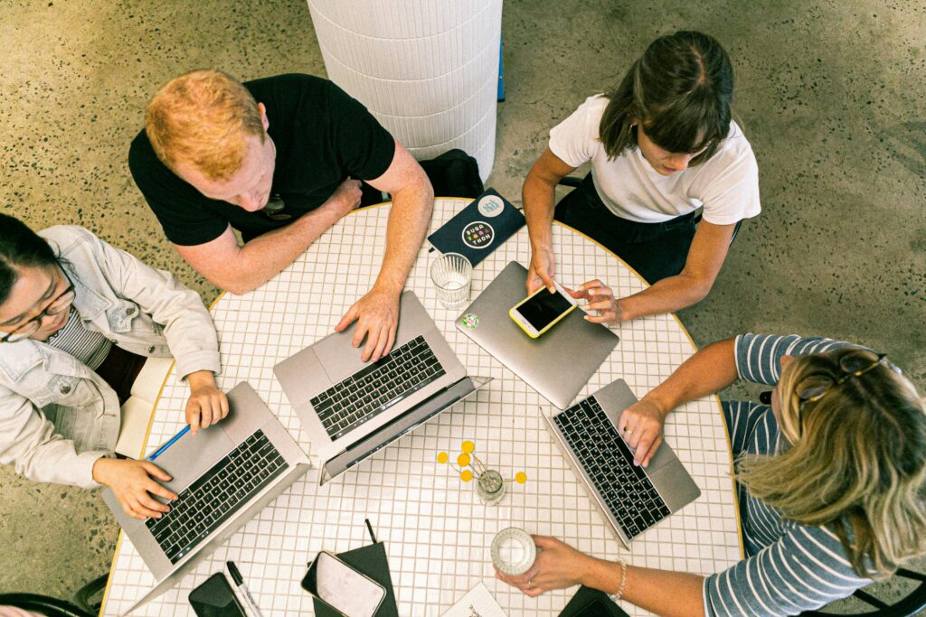 pexels-photo-3277808-3277808 Top view of team collaborating in a modern office around laptops, discussing ideas.